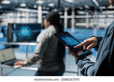 Close up of computer scientist in server hub using tablet to enhance AI model accuracy. Data center software developer using device to schedule maintenance for AI hardware rigs