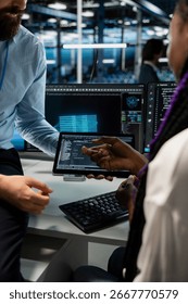 Close up of computer scientists coding on tablet in data center, updating AI automation scripts. Coworkers in server room programming artificial intelligence algorithms, debugging rigs