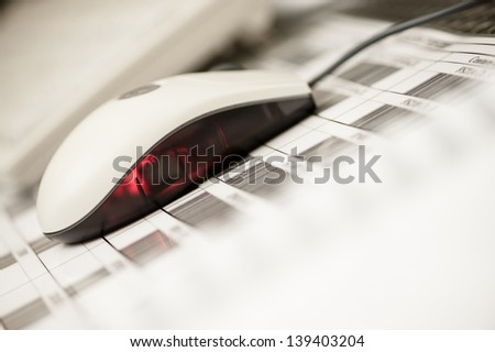 Close of a computermouse lying on a paper with barcodes