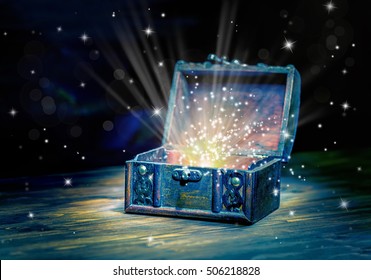 close up concept greeting card of opened vintage chest treasure with mystical miracle light on wooden background, beautiful fine art design 