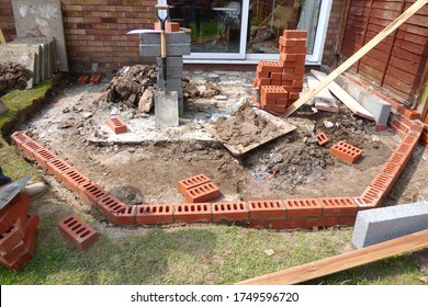 Close Up Of Concrete And Brick Foundation For Conservatory Base For House Extension With Tools And Supplies In Garden With Patio Doors Summer Sun