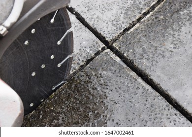 A close up of a concrete cutting blade making a cut deep into a concrete driveway