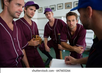 Close up of confident baseball team planning with coach while standing at locker room - Powered by Shutterstock