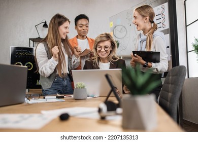 Close Up Of Confident Multiethnic Businesswomen With Senior Female Leader, Working Together In Office, Using Laptop And Tablet Pc, Discussing Business Strategy Or New Startup