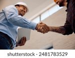 Close up of construction site worker and inspector handshaking at renovating house. 