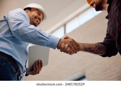 Close up of construction site worker and inspector handshaking at renovating house.  - Powered by Shutterstock