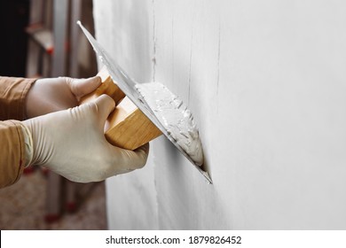 Close up of construction worker hands plastering and smoothing wall with a trowel. House renovation concept. 