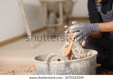 Close up of a construction worker hands removing debris to a carrycot in a house under renovation