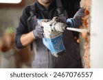 Close up of a construction worker using rotary hammer to wreck wall in a house under renovation