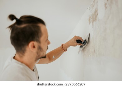 Close up of a constructor doing plasterwork and skim coating walls while using trowel. A worker is plastering walls and renovating the house while using building tools and plaster. Copy space.