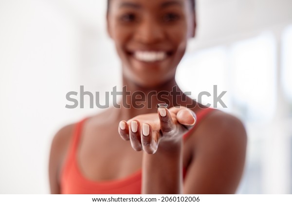 Close up of contact lens on\
finger of young african woman. Mature black woman holding contact\
lens in front of her face. Happy smiling woman showing contact\
lens.