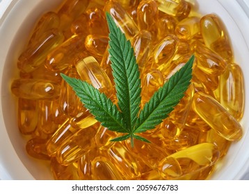 Close Up Of Container Filled With CBD Soft Gel Capsules And Cannabis Leaf, Alternative Medicine