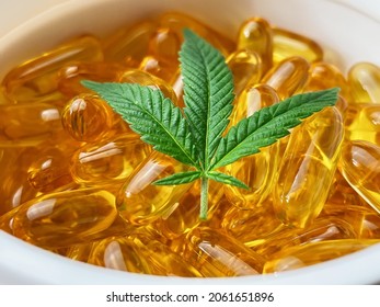 Close Up Of Container Filled With CBD Soft Gel Capsules And Cannabis Leaf, Alternative Medicine