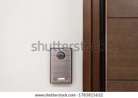 Close up of contemporary doorbell near door with security panel, intercom and video camera in modern house against white copy space wall