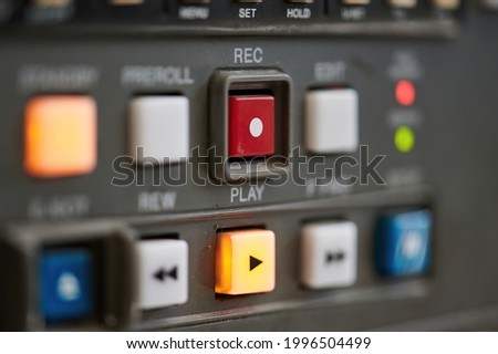 Close up of the control panel of an old broadcast tape recorder where we can see the playback buttons and the focus on the red rec button.
