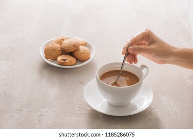 close up of cookie and hand stirring cup of tea/coffee - Powered by Shutterstock