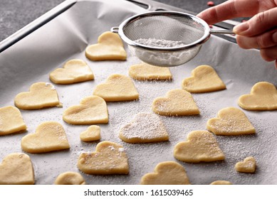 Close Up Cookies Hearts On Parchment Paper On Baking Sheet Sprinkle Powdered Sugar On Top Through Strainer