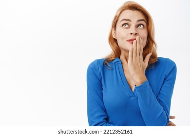 Close Up Of Coquettish Woman Giggle, Hears Gossip, Looks Amazed By Rumour, Stands Over White Background Intrigued