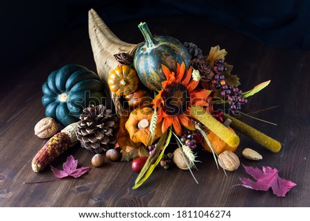 Close up of a cornucopia centrepiece filled with various autumn decorations