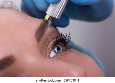 Close up of a cosmetologist applying a special permanent make up on a woman's eyebrows.