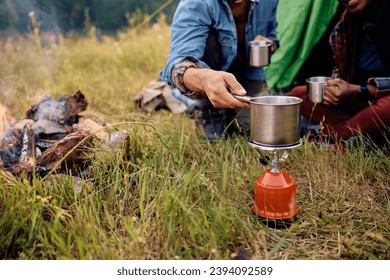 Close up of couple of campers preparing tea on on portable gas burner in nature. Copy space. - Powered by Shutterstock