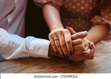 Close up of couple hands on restaurant table. Romantic couple holding each other's hand in cafe. Marriage proposal and engagement concept.