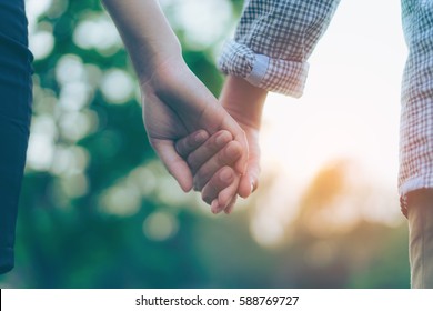 Close up of a couple holding hands. Hand-in-hand. Couple love in forest.