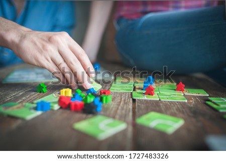 Close up of a couple in love sitting on the floor next to a table, playing ludo board game and enjoying their free time together. Focus on the red figurine