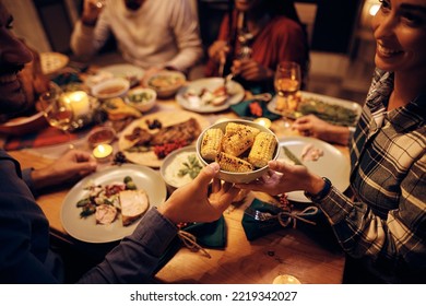 Close Up Of Couple Passing Food While Having A Meal With Friends On Thanksgiving.