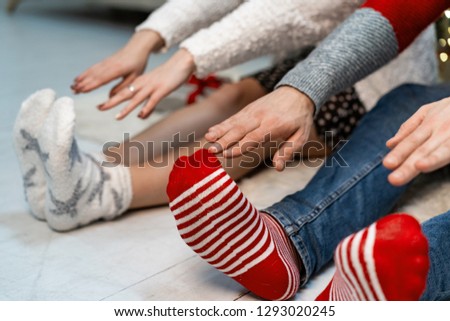 Close up of couple that stretching their arms to their feets, christmas socks.