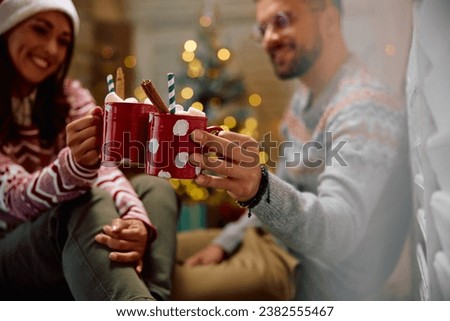 Close up of couple toasting with hot chocolate at Christmas at home. Copy space.