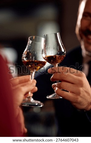 Close up of couple toasting while drinking brandy while celebrating in a bar.
