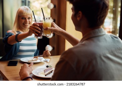 Close up of couple toasting while enjoying in a cafe.