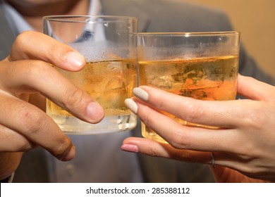 Close Up Of Couple Toasting Whiskey Glasses