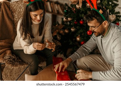 Close up of couple wrapping gift boxes on Christmas morning at home. - Powered by Shutterstock