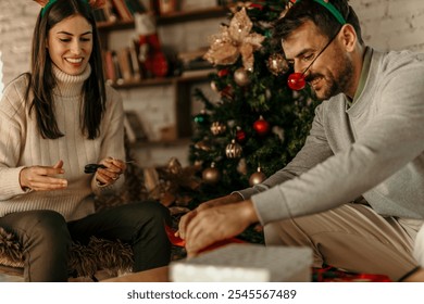 Close up of couple wrapping gift boxes on Christmas morning at home. - Powered by Shutterstock