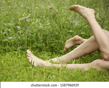 Close Up Of Couple's Bare Feet And Legs In Meadow