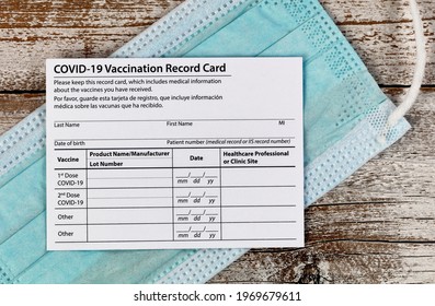 Close Up Of A Covid 19 Vaccination Record Card Place On Personal Facemask.  Individual Record For Use During The Covid 19 Coronavirus Global Pandemic 