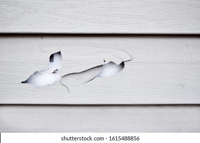 Close Up Of A Cracked And Broken Beige Vinyl Siding Of A House