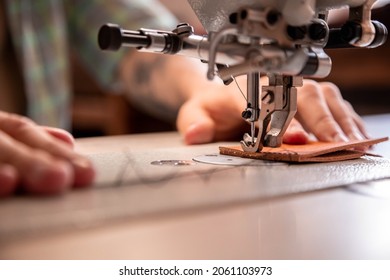 Close up craftsman hands sew natural stuff blank for wallet use sewing machine with needle. Male tanner connecting details creating quality leatherwork accessories. Working process at leather workshop - Powered by Shutterstock