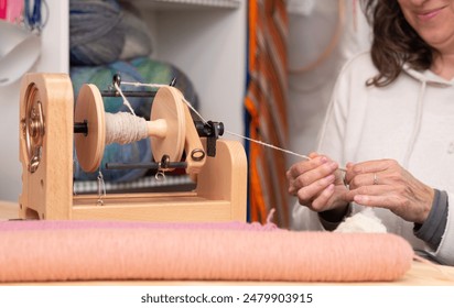 Close up of a craftswoman spinning  wool with an electric spinning wheel in her knitting store. - Powered by Shutterstock