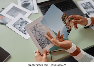 Close up of creative team holding printed photographs with nature landscapes and collaborating on editors project copy space - Powered by Shutterstock