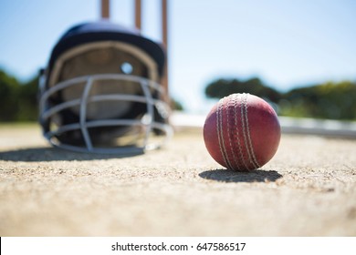 Close Up Of Cricket Ball With Helmet On Pitch During Sunny Day