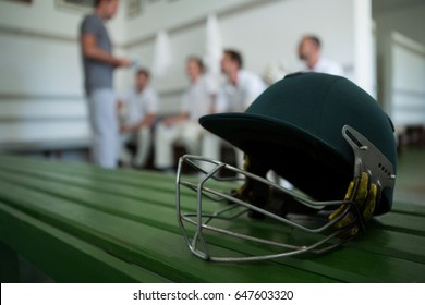 Close up of cricket helmet on table against team in locker room - Powered by Shutterstock