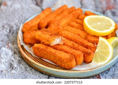 Close up of   Crispy breaded  deep fried fish fingers with breadcrumbs served  with remoulade sauce and  lemon Cod Fish Nuggets on rustic wood table background - Shutterstock ID 2207377113