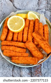 Close up of   Crispy breaded  deep fried fish fingers with breadcrumbs served  with remoulade sauce and  lemon Cod Fish Nuggets on rustic wood table background - Shutterstock ID 2207377115