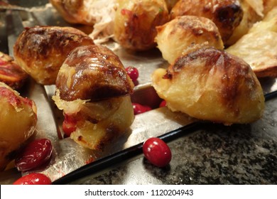 Close Up Crispy Roasted Potatoes And Fresh Cranberries On Messy Dark Kitchen Worktop. Photo Is Intentional Taken Side Angle To Show Some Space Of The Marble Top. Some Turkey Meat Mixing In Background.