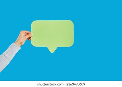 Close Up Crop Of Woman Hand Hold Speech Bubble With Empty Blank Copy Space For Advertising. Female Show Talk Balloon Recommend Deal Or Offer. Blue Studio Background Isolated.