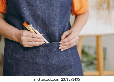 Close up cropped artist woman 50 years old wearing casual clothes stand near easel with painting artwork hold put into pocket brushes spend free spare time in living room indoor. Leisure hobby concept - Powered by Shutterstock