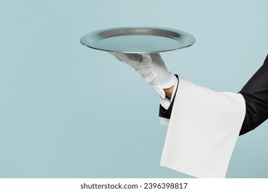 Close up cropped barista male waiter hold in hand plate with empty tray isolated on pastel plain light blue color wall background studio. Restaurant employee concept. Copy space advertising mock up